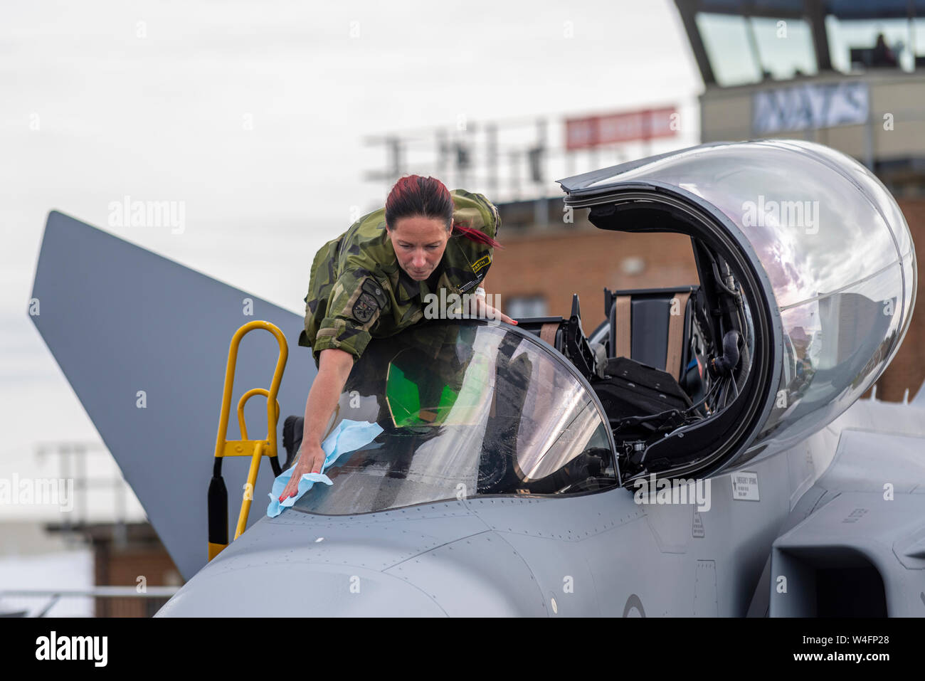 Membre de l'équipage féminin de l'armée de l'air suédoise nettoyant le pare-brise du cockpit de l'avion Gripen au salon aérien Royal International Air Tattoo, RAF Fairford, Royaume-Uni. Banque D'Images