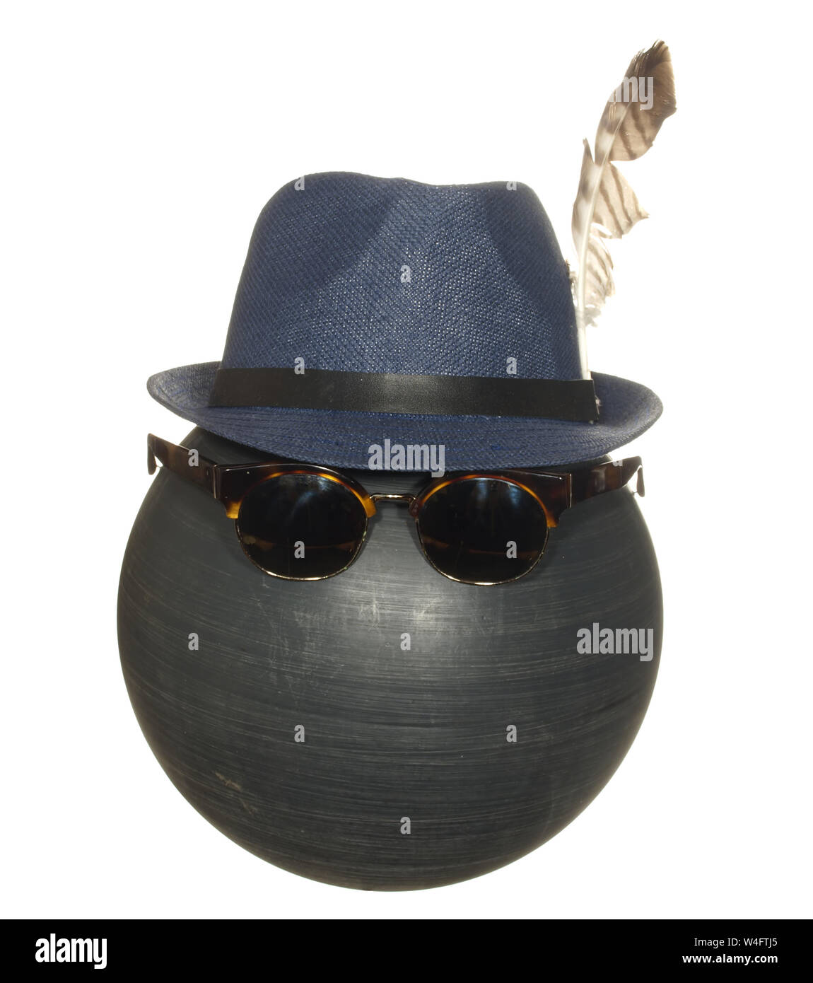 Men's chapeau bleu avec une plume d'oiseau et des lunettes sombres sur une balle de plastique noir isolé sur fond blanc. Banque D'Images