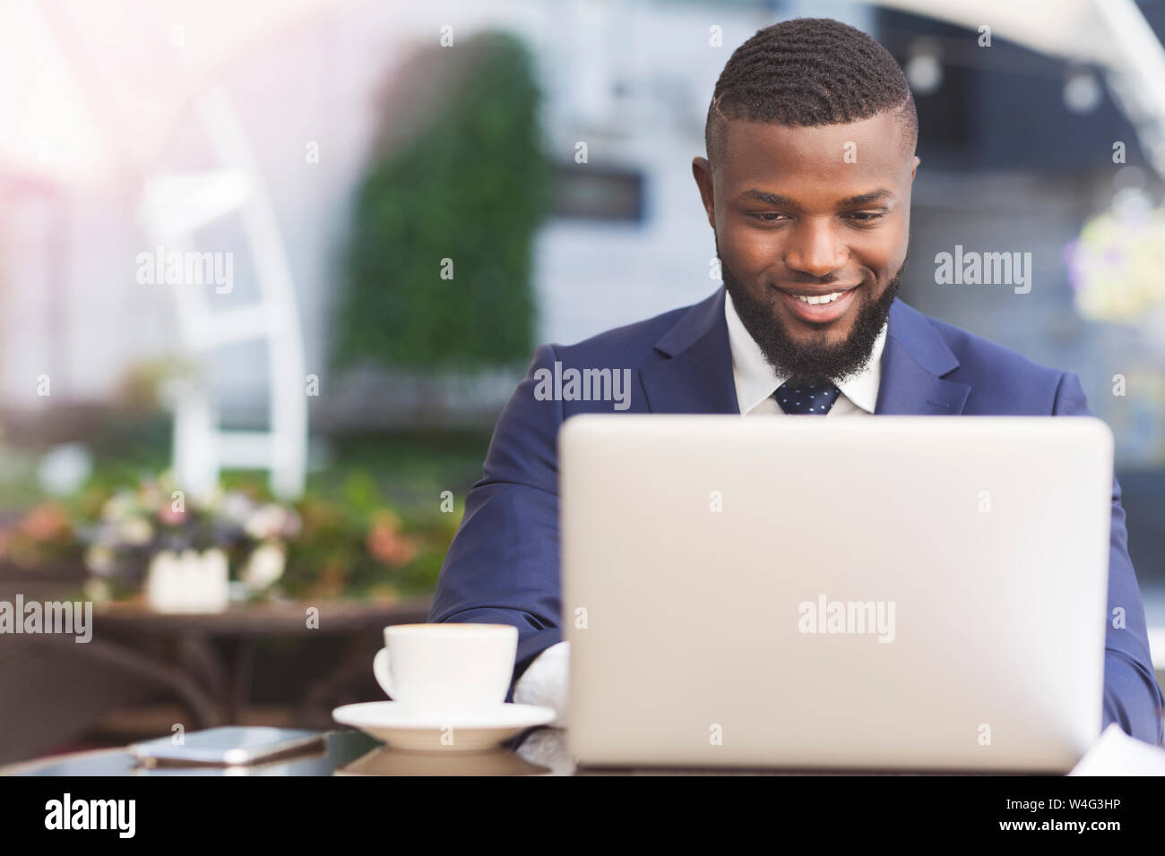 Smiling African American Businessman Working On Laptop in Outdoor Cafe Banque D'Images