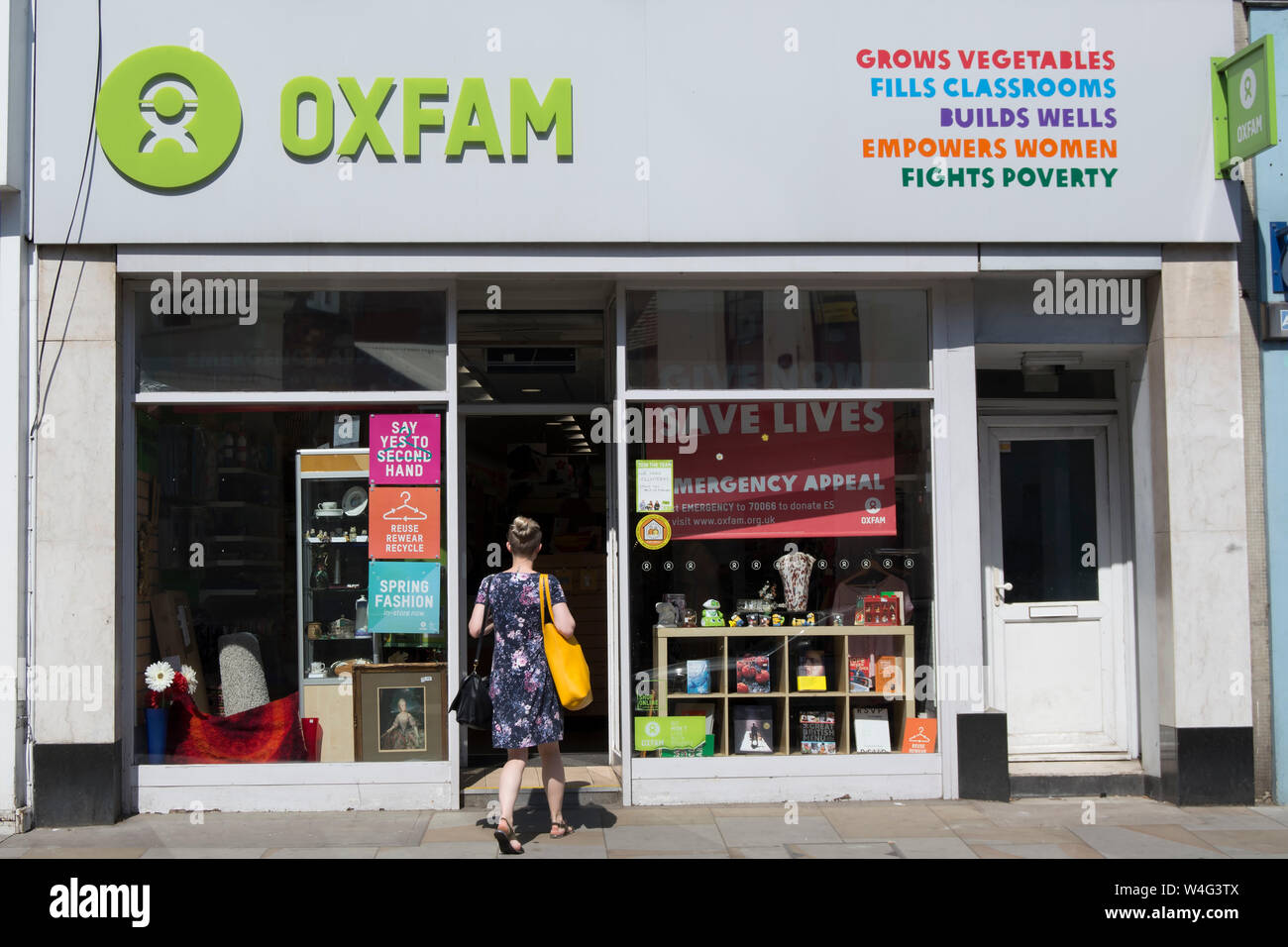 Une femme entre dans une succursale d'un magasin de charité oxfam à Richmond, Surrey, Angleterre Banque D'Images