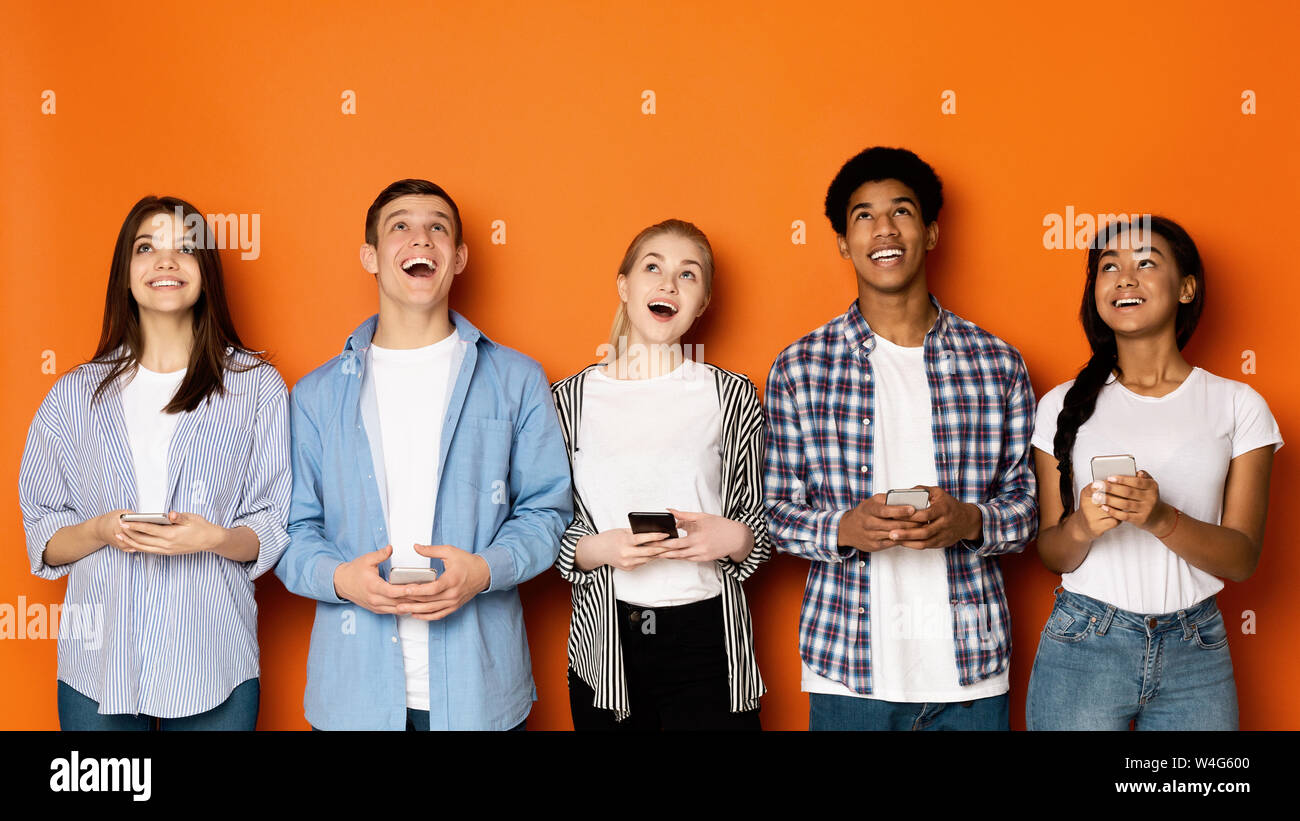Les amis avec les smartphones looking up on copy space Banque D'Images