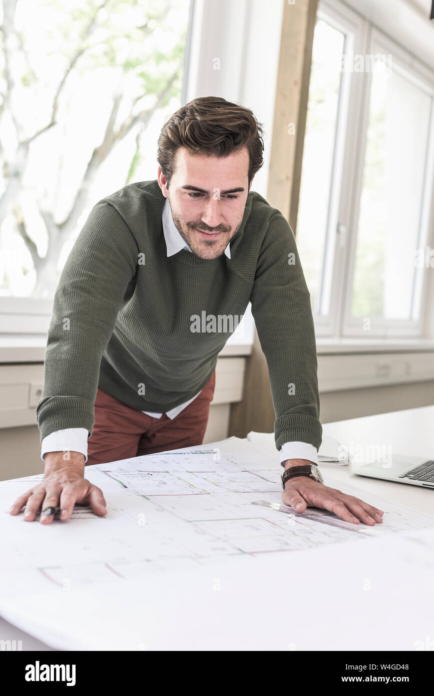 Jeune architecte travaillant sur blueprint in bright office Banque D'Images