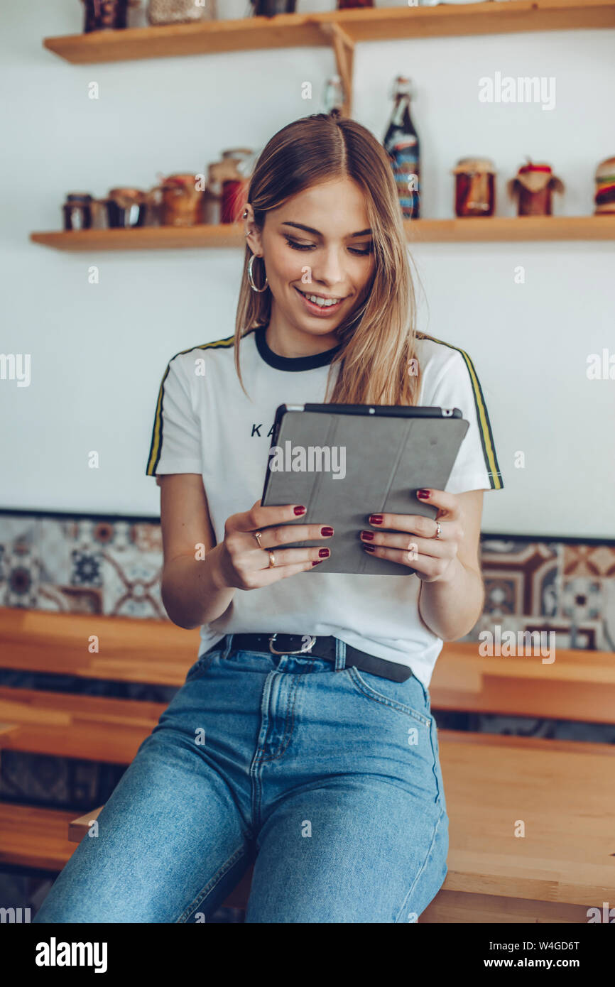 Portrait of young woman smiling en utilisant une tablette dans un café Banque D'Images
