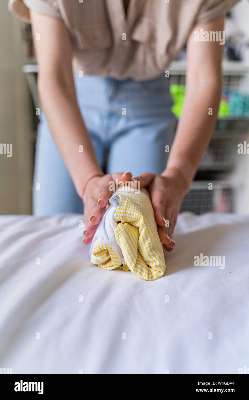 Close-up of woman folding clothes on bed Banque D'Images