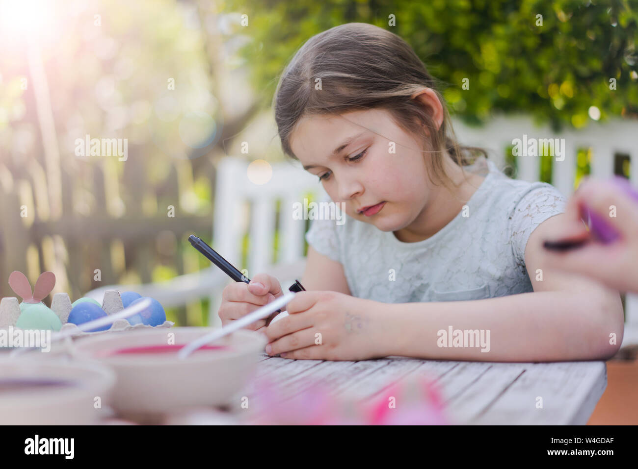 Girl painting easter egg sur table de jardin Banque D'Images