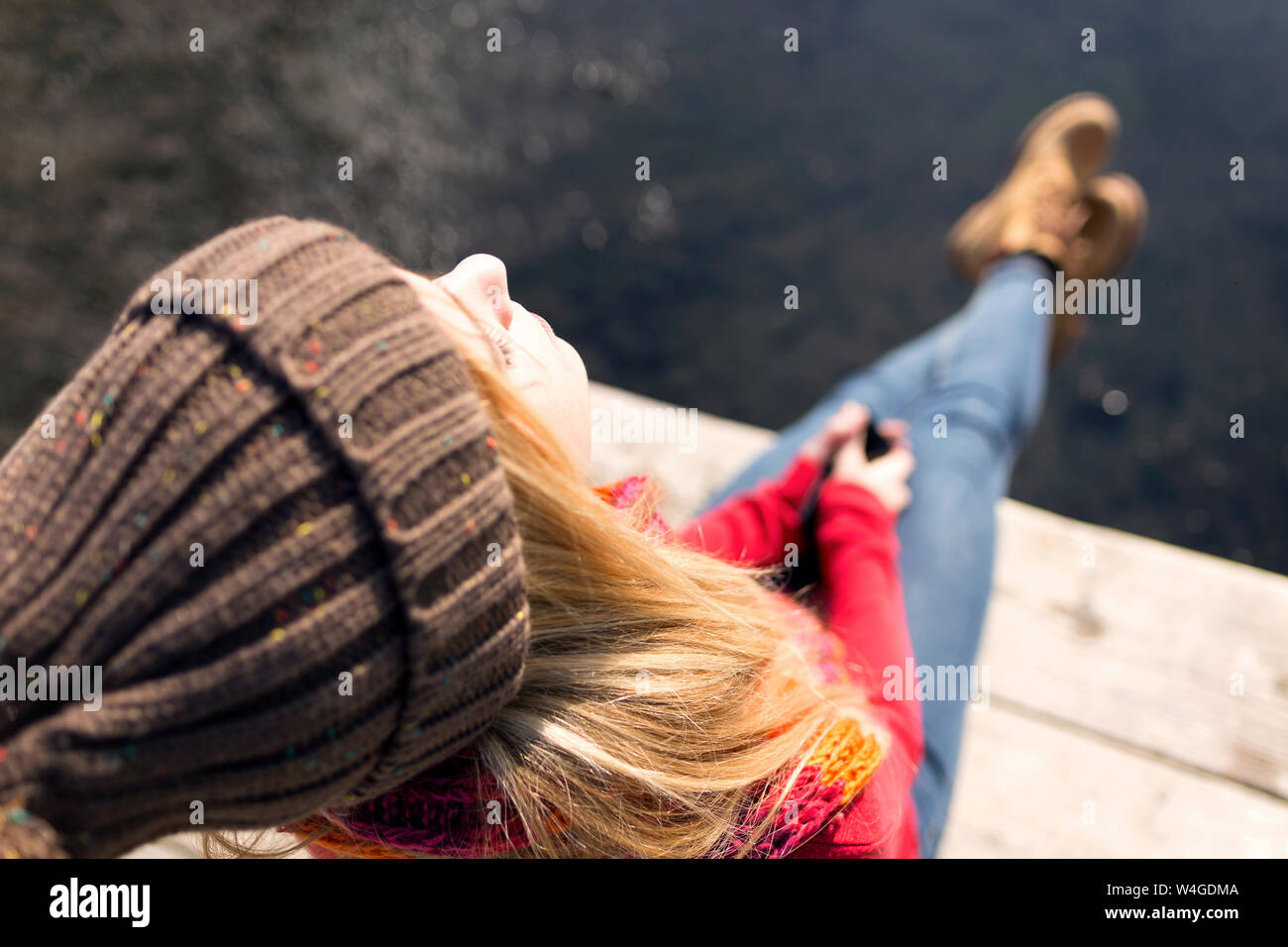 Young blonde woman with smartphone à un lac en hiver Banque D'Images
