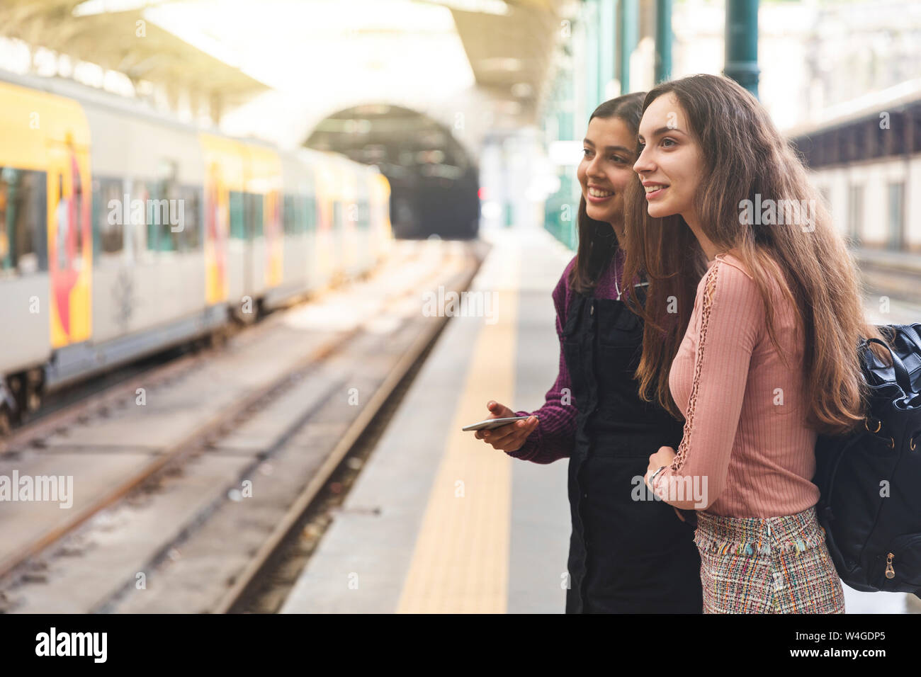 Deux jeunes femmes avec sac à dos et cell phone standing on platform regarder quelque chose, Porto, Portugal Banque D'Images