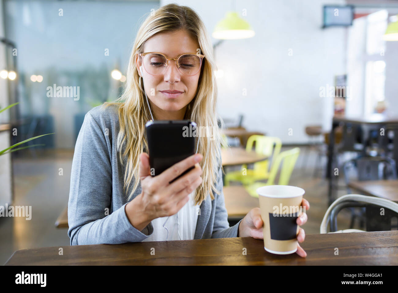 Jeune femme textos avec son téléphone portable alors que la consommation de café dans le café Banque D'Images