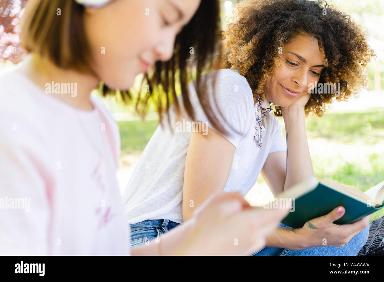 Smiling woman with book relaxing in park Banque D'Images
