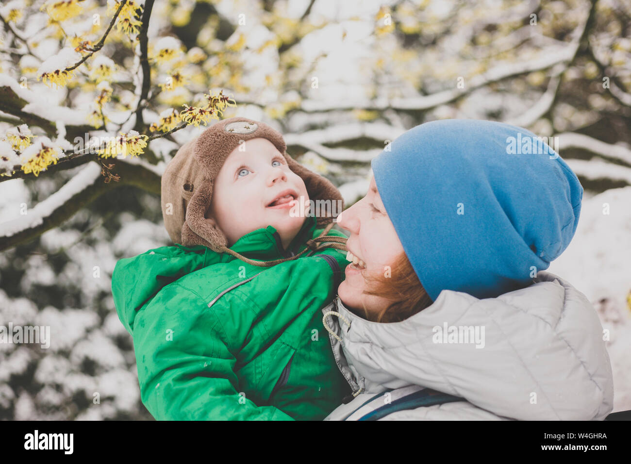 Portrait de petit garçon apprécie sa première neige sur les bras de sa mère Banque D'Images