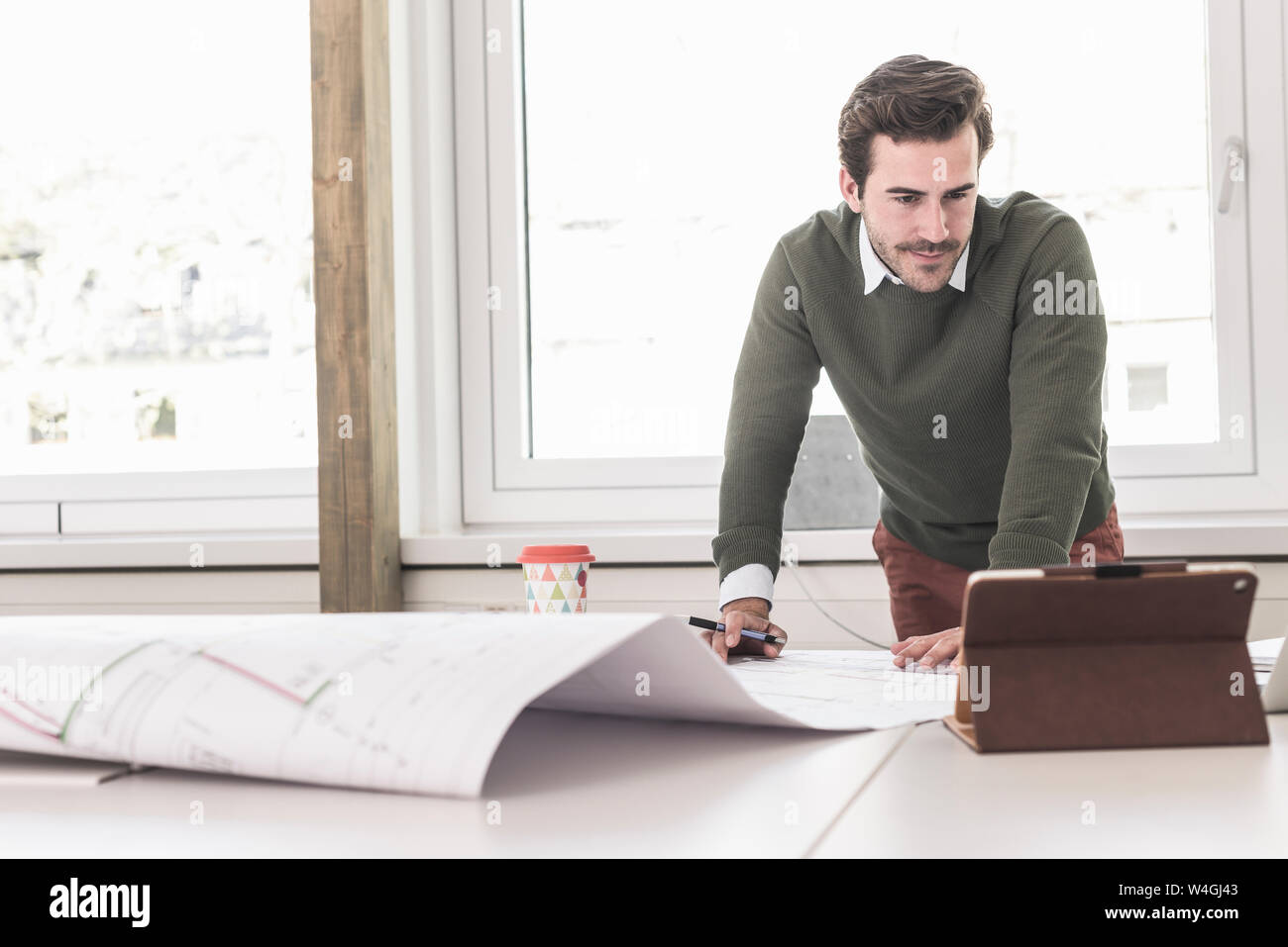 Jeune architecte travaillant sur blueprint in bright office Banque D'Images