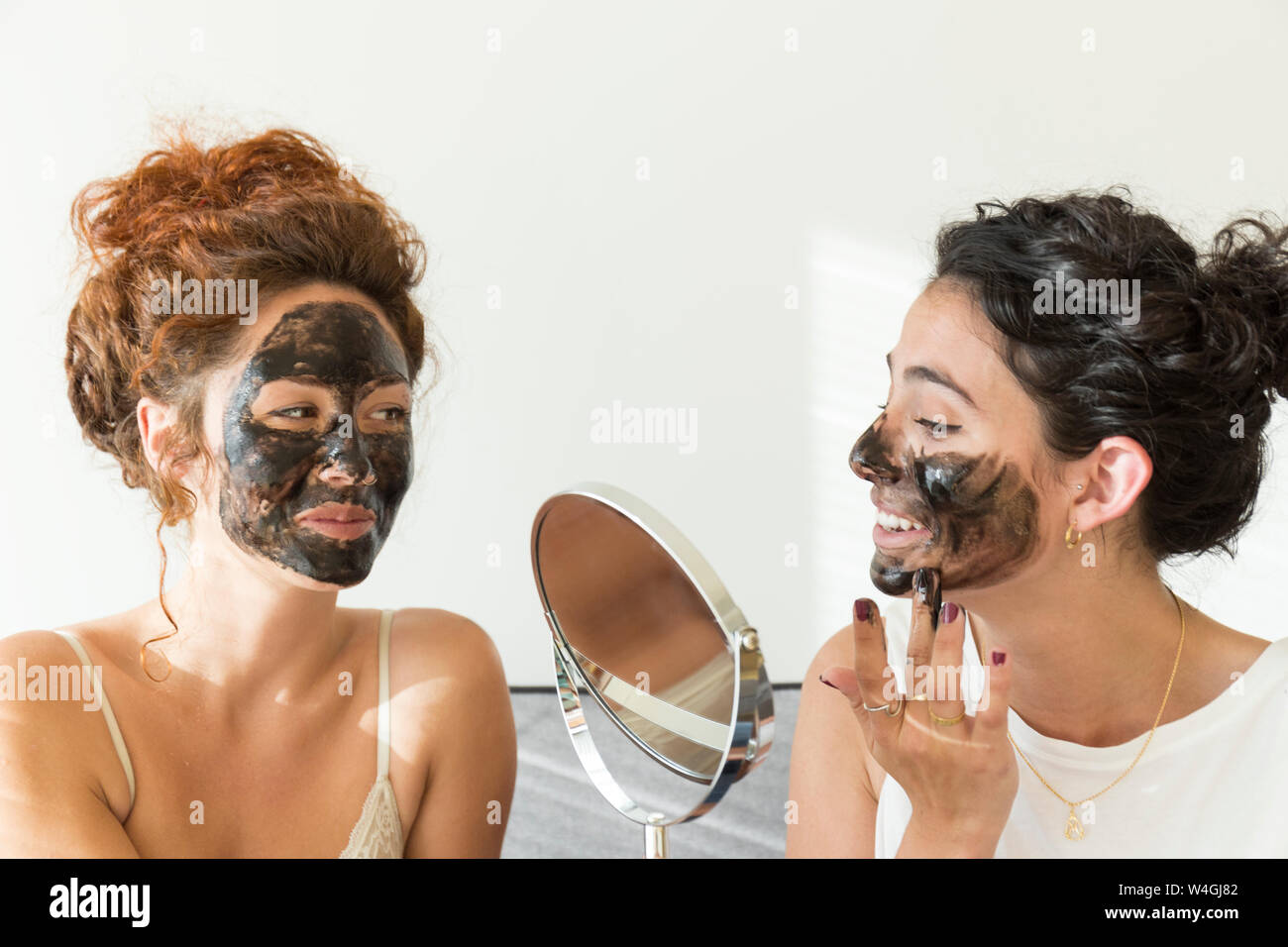 Deux professionnels des jeunes femmes l'application de masques visage à la maison Banque D'Images