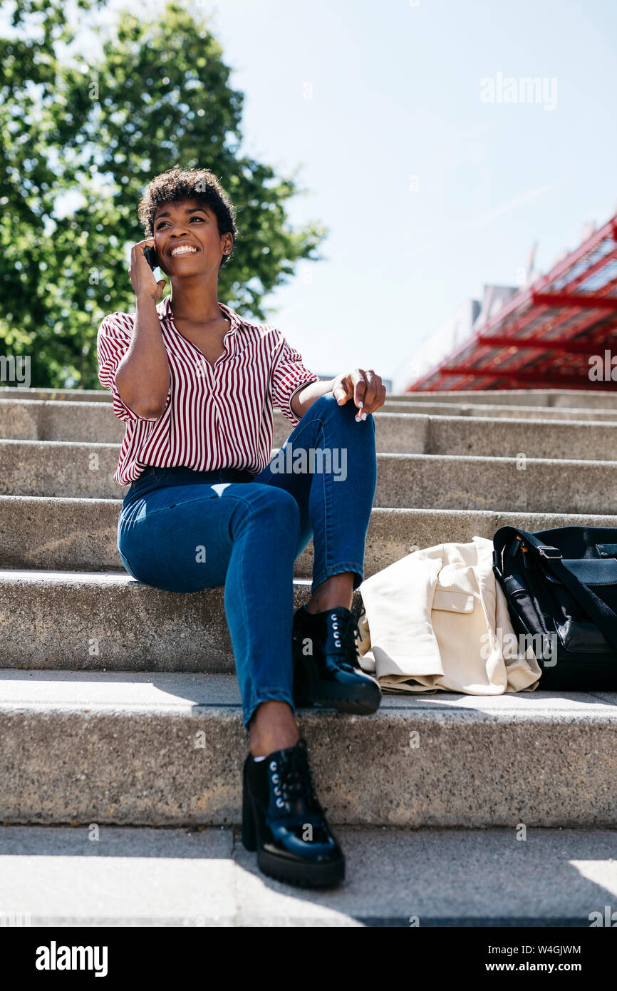 Businesswoman using smartphone, sitting on stairs Banque D'Images