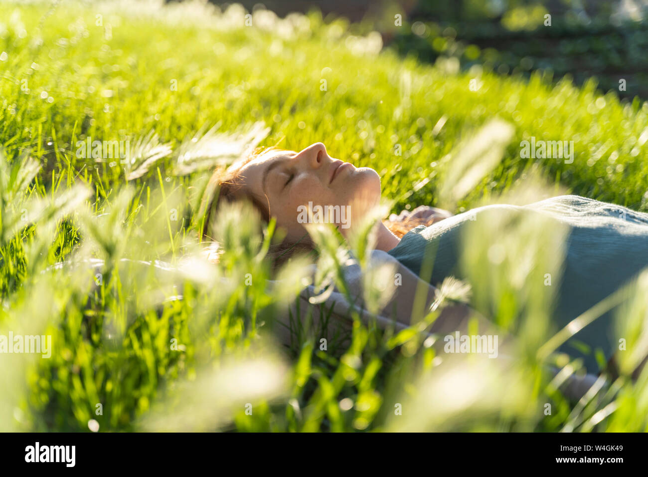 Jeune femme rousse allongée sur prairie dans un parc Banque D'Images