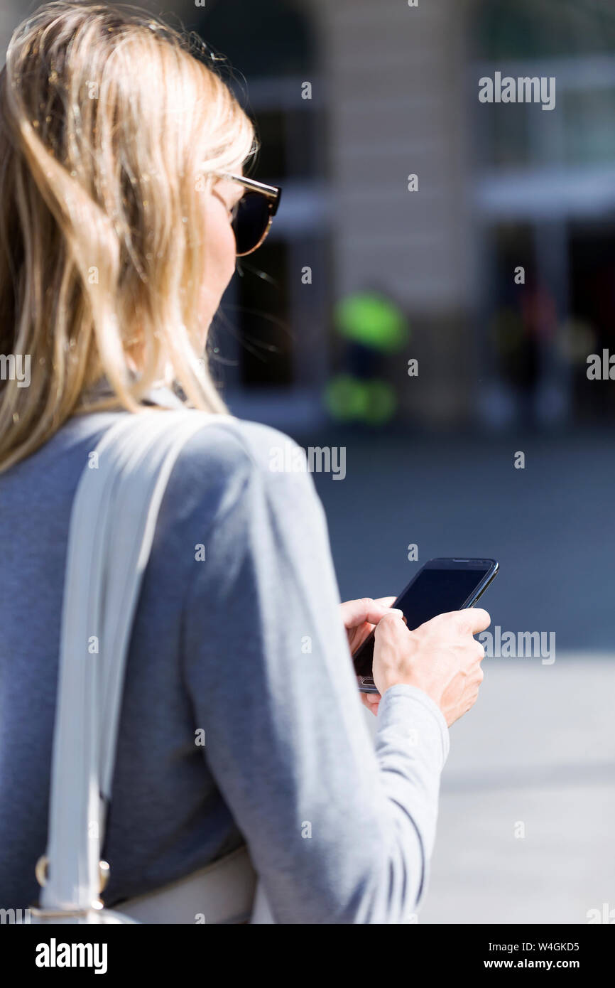 Young businesswoman texting avec son téléphone mobile en marchant Banque D'Images