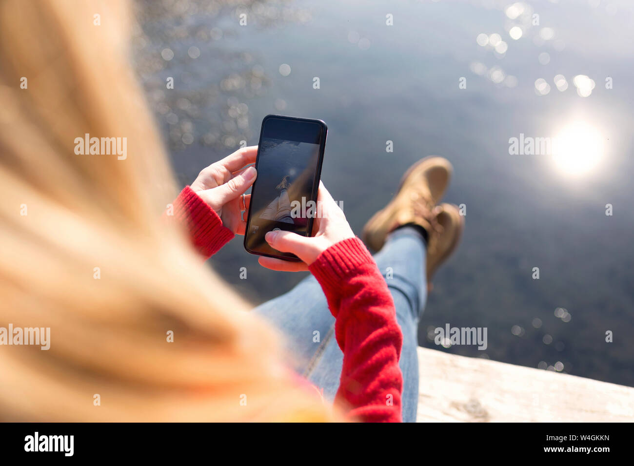 Jeune femme blonde en utilisant smartphone à un lac en hiver Banque D'Images