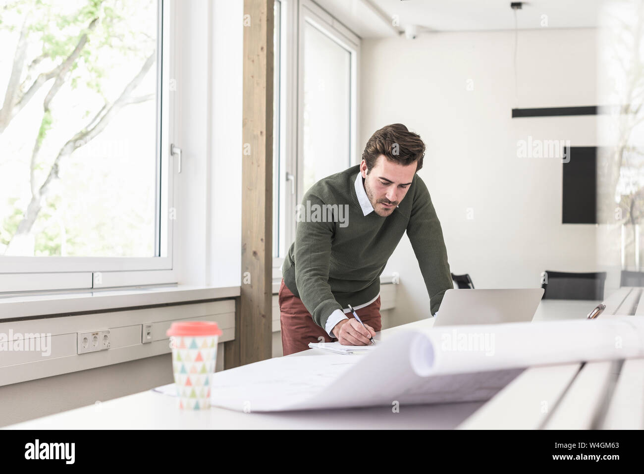 Jeune architecte travaillant sur blueprint in bright office Banque D'Images