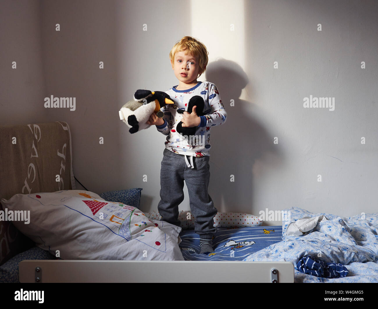 Portrait de petit garçon debout sur son lit avec des jouets mous Banque D'Images