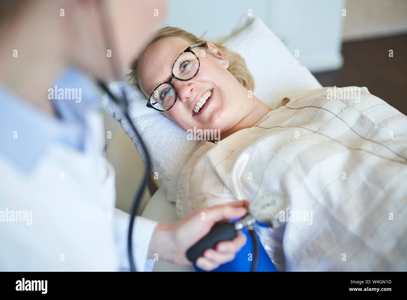Smiling patient médecin de prendre la tension artérielle dans la pratique médicale Banque D'Images