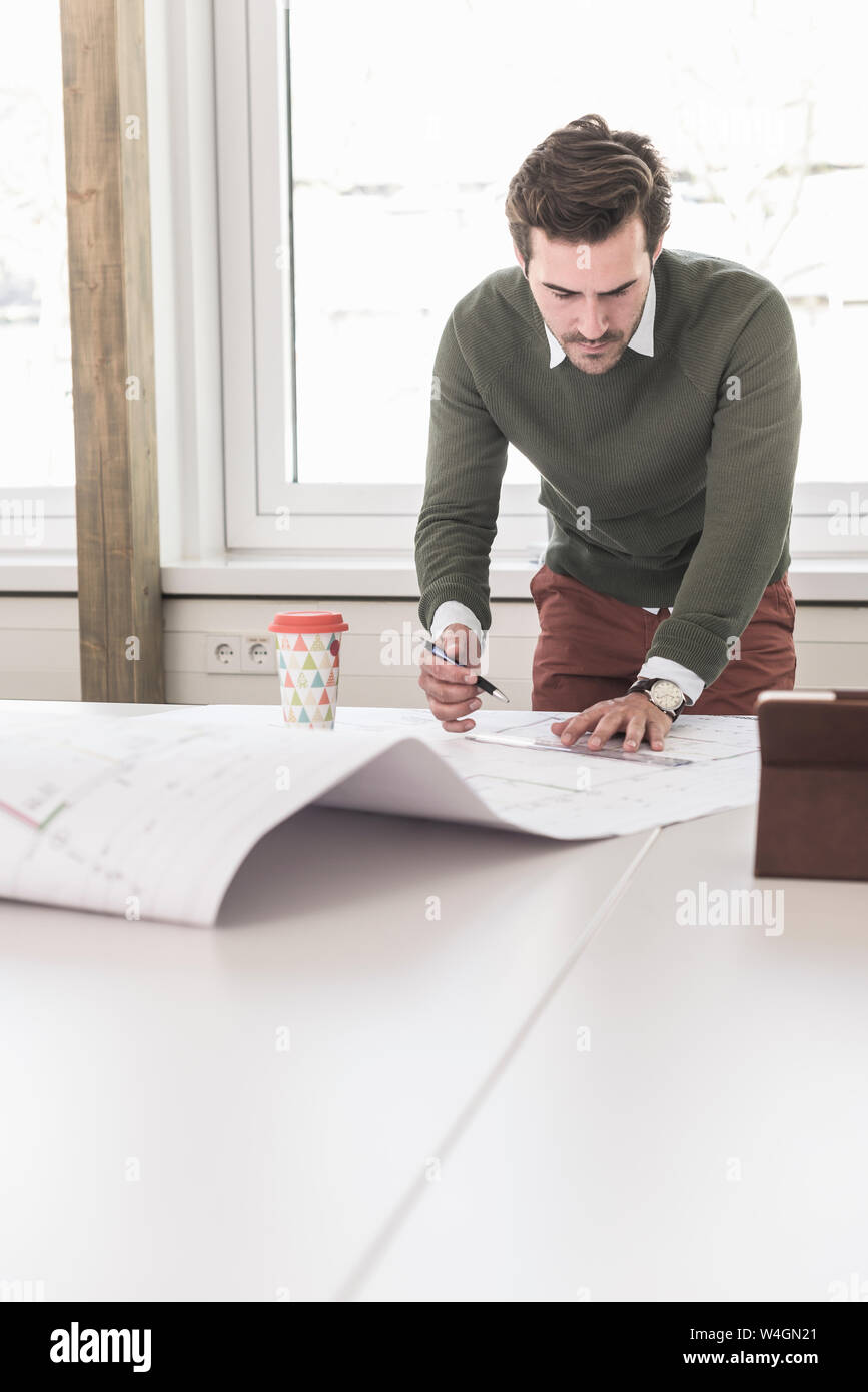 Jeune architecte travaillant sur blueprint in bright office Banque D'Images