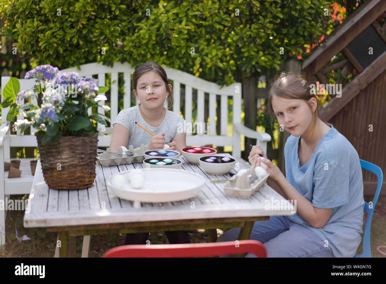 Portrait de deux jeunes filles à la teinture des oeufs de Pâques sur table de jardin Banque D'Images