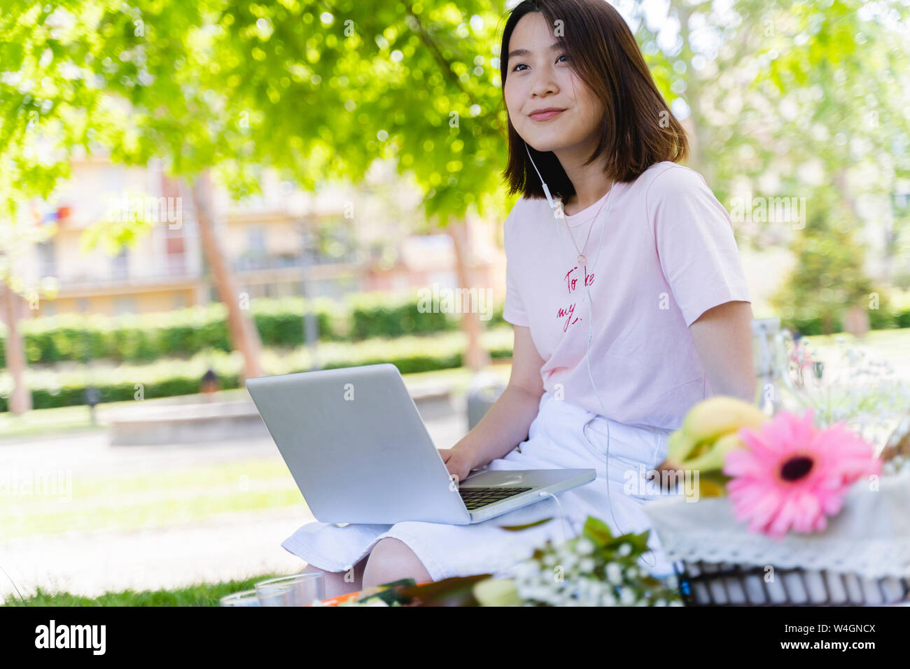 Jeune femme avec un ordinateur portable et d'écouteurs un pique-nique dans le parc Banque D'Images