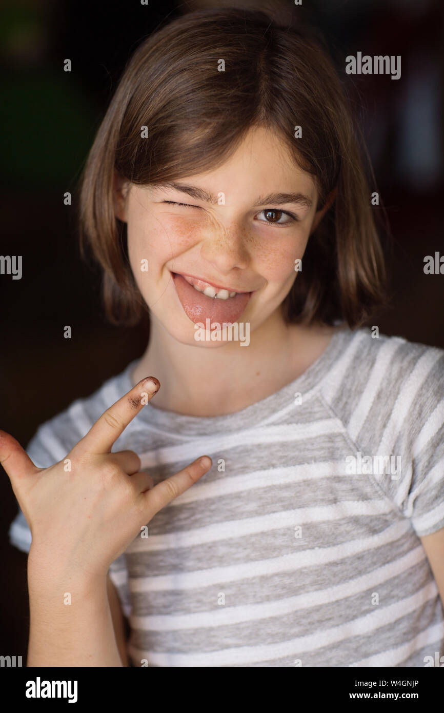 Portrait de jeune fille, avec un clin d'sticking out tongue, rock and roll sign Banque D'Images