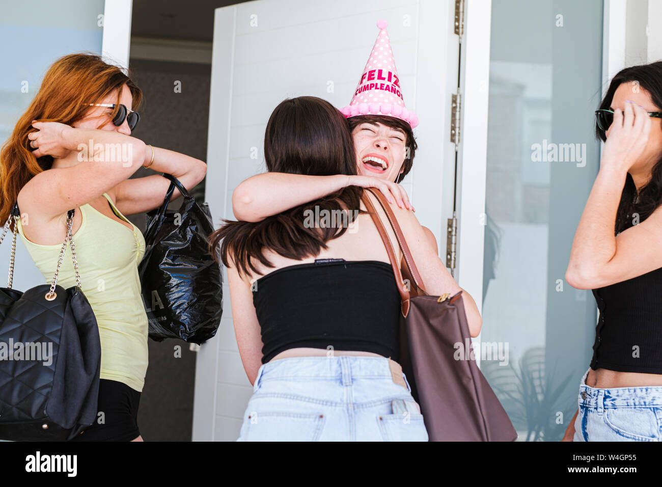 Girlfriends celebrating birthday, surprenant d'amis l'enfant d'anniversaire sur la porte Banque D'Images