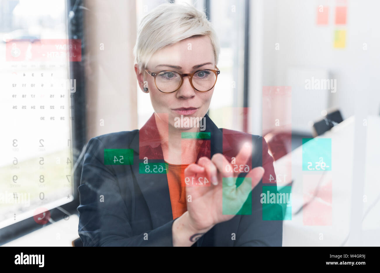 Businesswoman touching glass wall avec data in office Banque D'Images