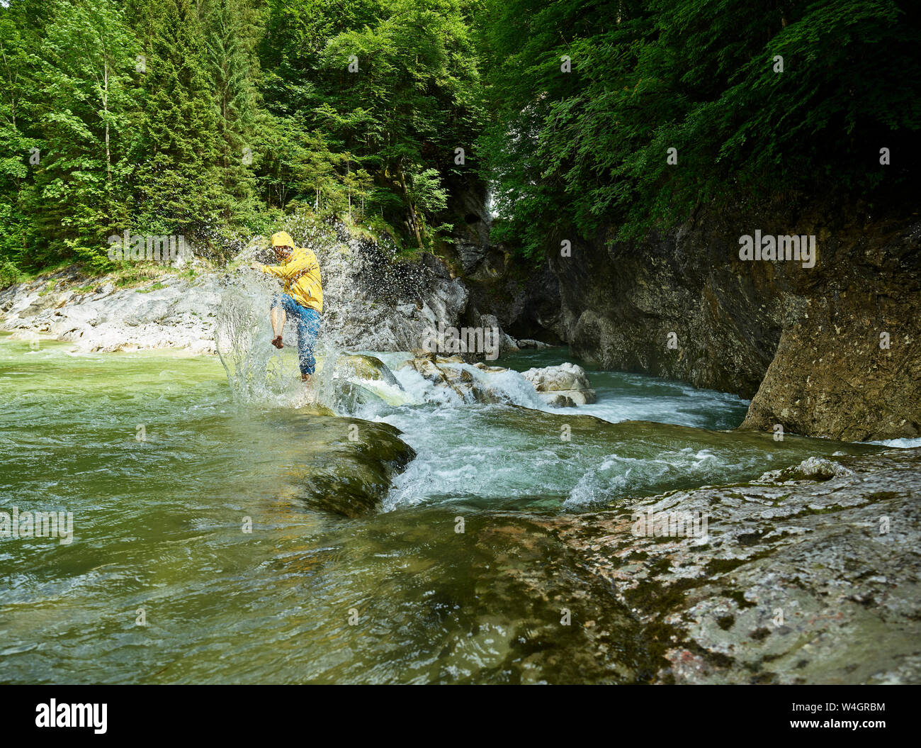 Autriche, Tyrol, Brandenberg, man crossing Brandenberger Ache, splash Banque D'Images