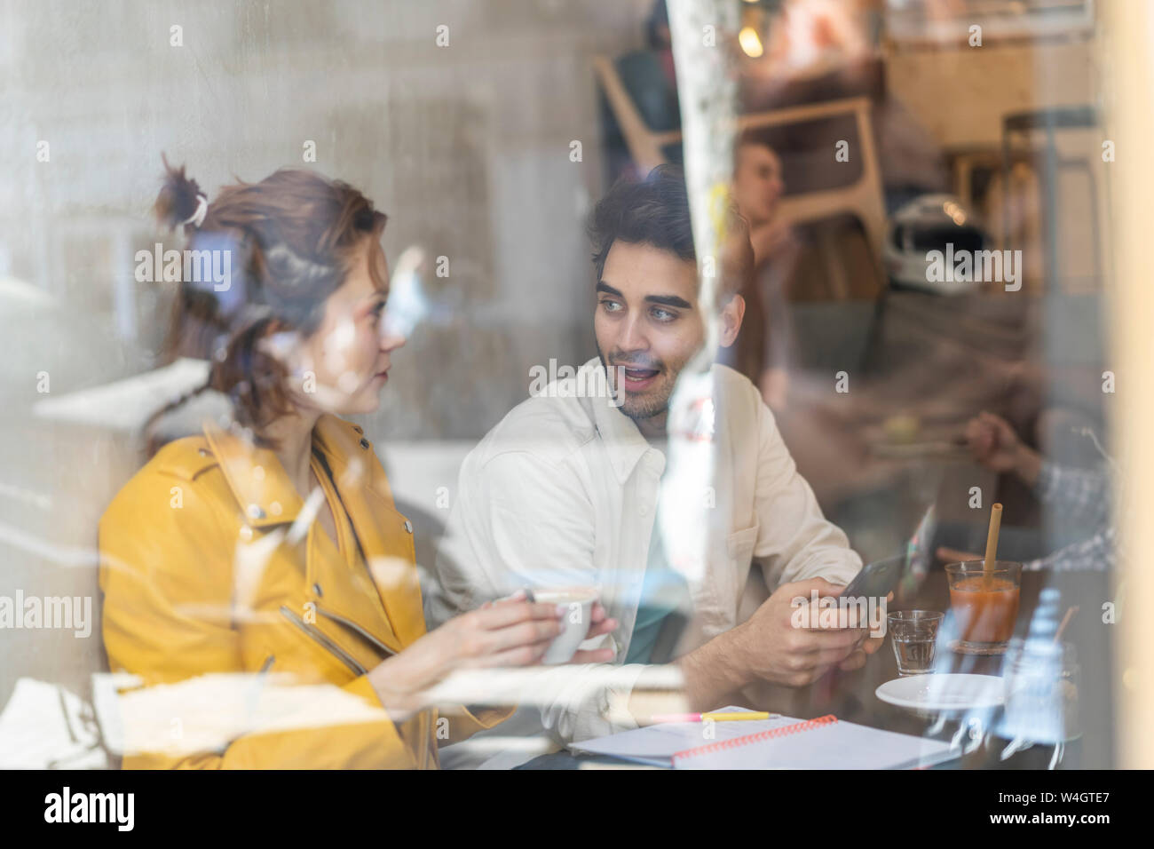 L'homme et la femme avec un téléphone mobile et ordinateur portable dans un café de la réunion Banque D'Images
