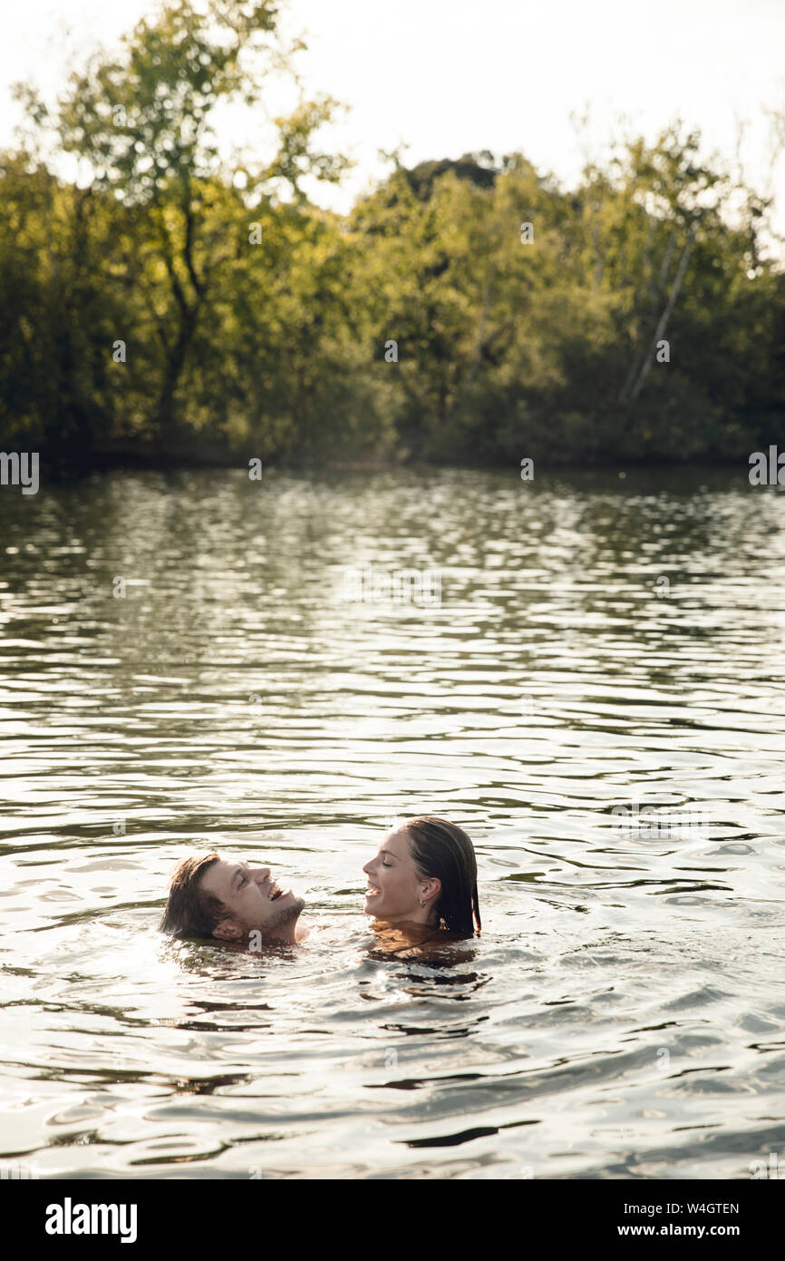 Affectionate couple nageant ensemble dans un lac Banque D'Images