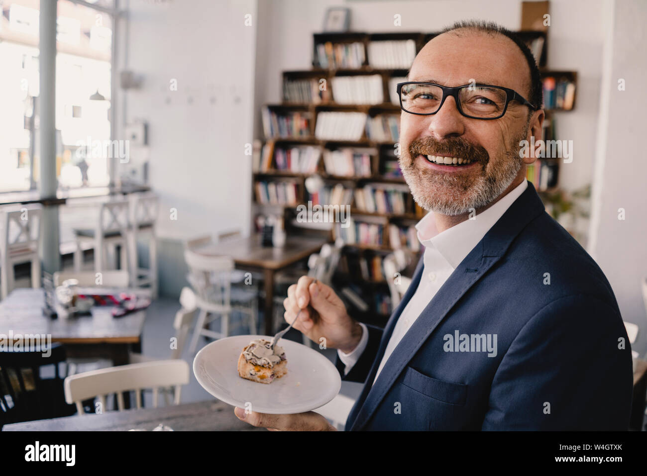 Smiling mature businessman having un morceau de gâteau dans un café Banque D'Images