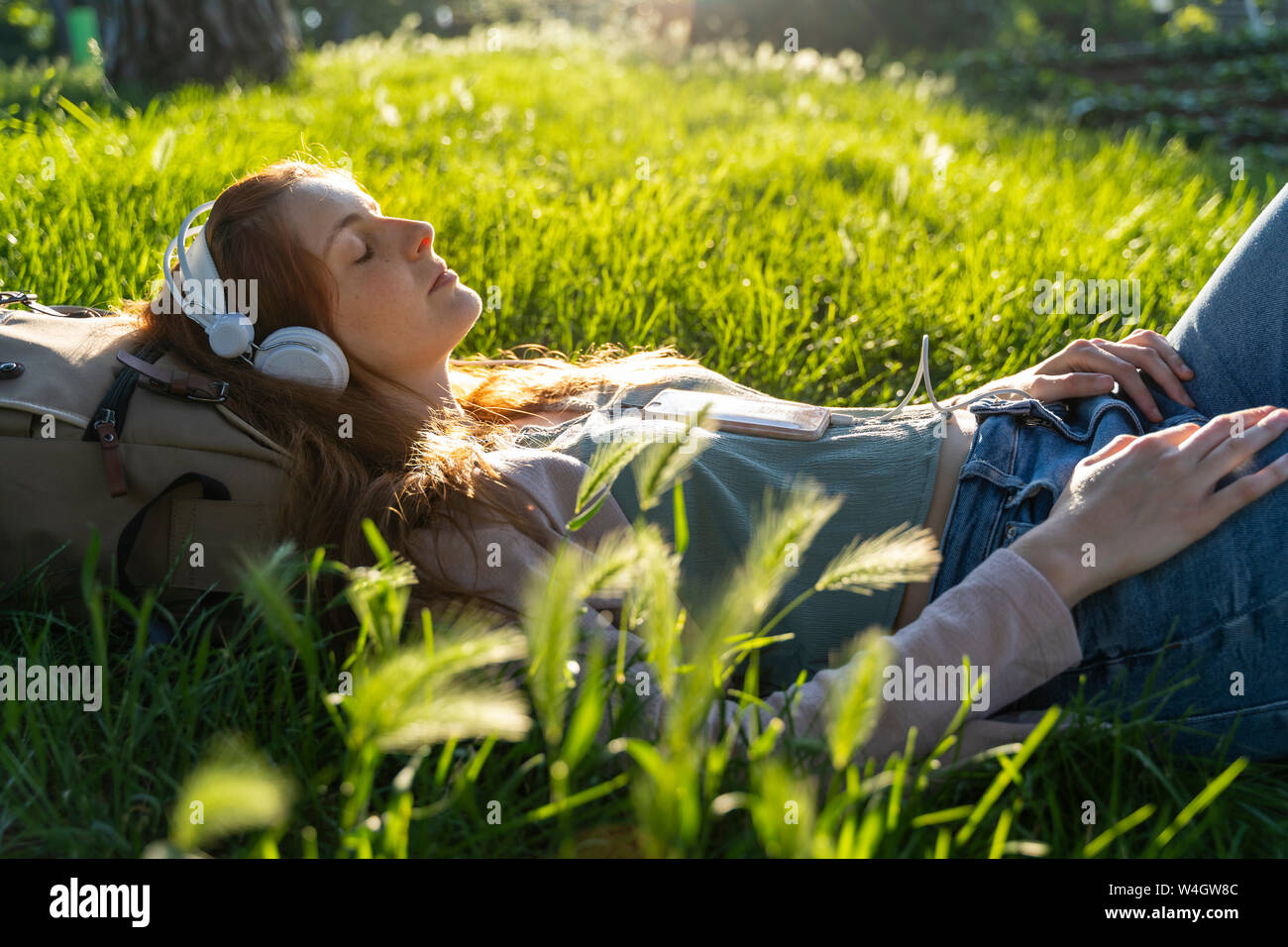 Jeune femme rousse au casque et le smartphone dans un parc Banque D'Images