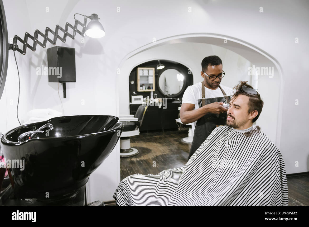 Coiffure raser et couper les cheveux d'un client dans un salon de coiffure Banque D'Images