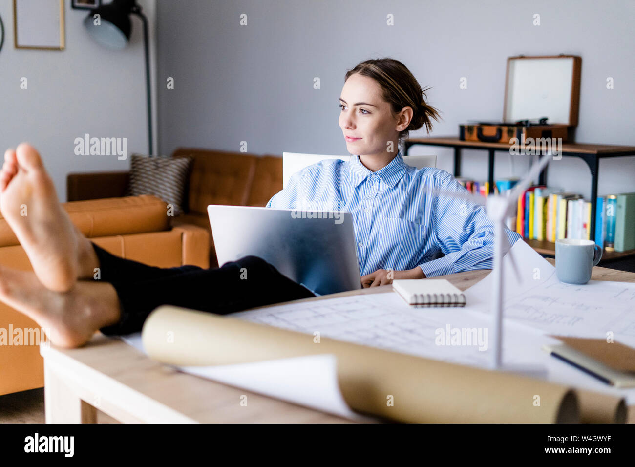 Woman in office working on laptop avec les pieds sur la table Banque D'Images