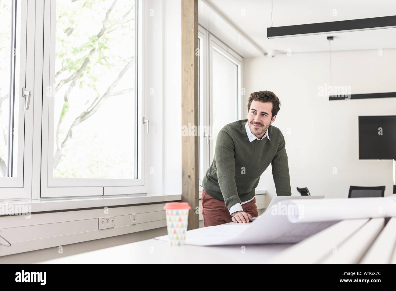 Jeune architecte travaillant sur blueprint in bright office Banque D'Images