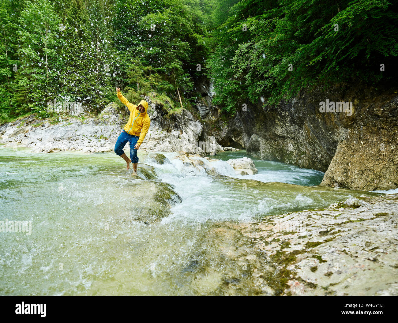 Autriche, Tyrol, Brandenberg, man crossing Brandenberger Ache, splash Banque D'Images