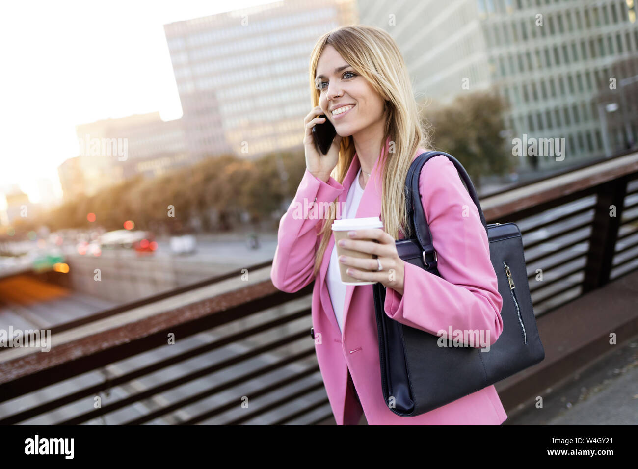 Young businesswoman using smartphone et holding coffee pour aller Banque D'Images
