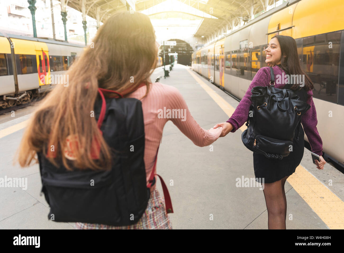 Vue arrière de deux jeunes femmes avec des sacs à main dans la main sur la plate-forme, Porto, Portugal Banque D'Images