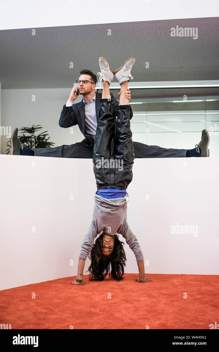 Businessman in office holding woman's legs faire un handstand Photo Stock -  Alamy