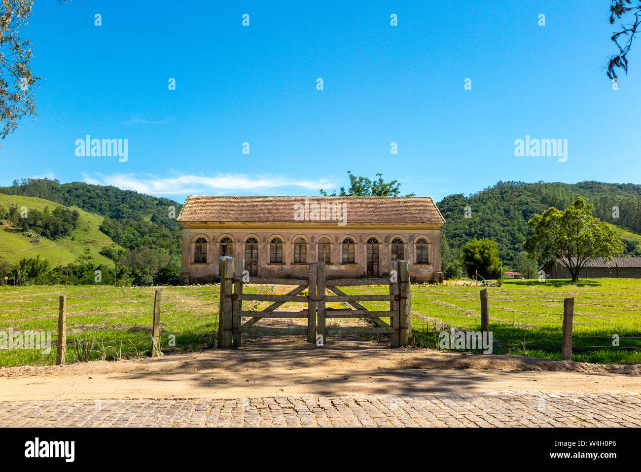 Vieille ferme abandonnée avec barrière en bois, pelouse, montagne en arrière-plan et ciel bleu, ville de Pedras Soltas, Santa Catatarina, Brésil Banque D'Images