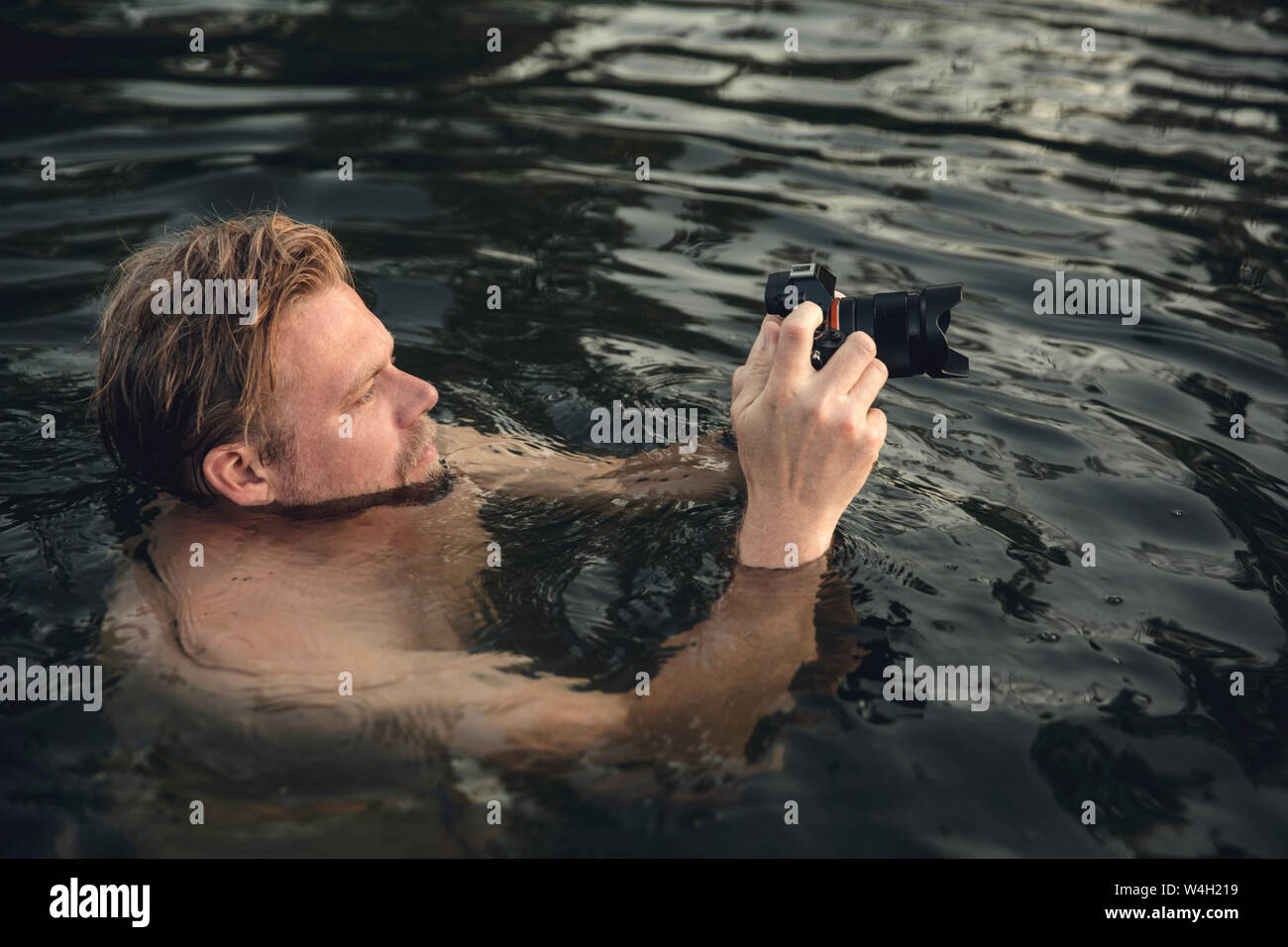 Homme natation dans le lac, prendre des photos avec son appareil photo Banque D'Images