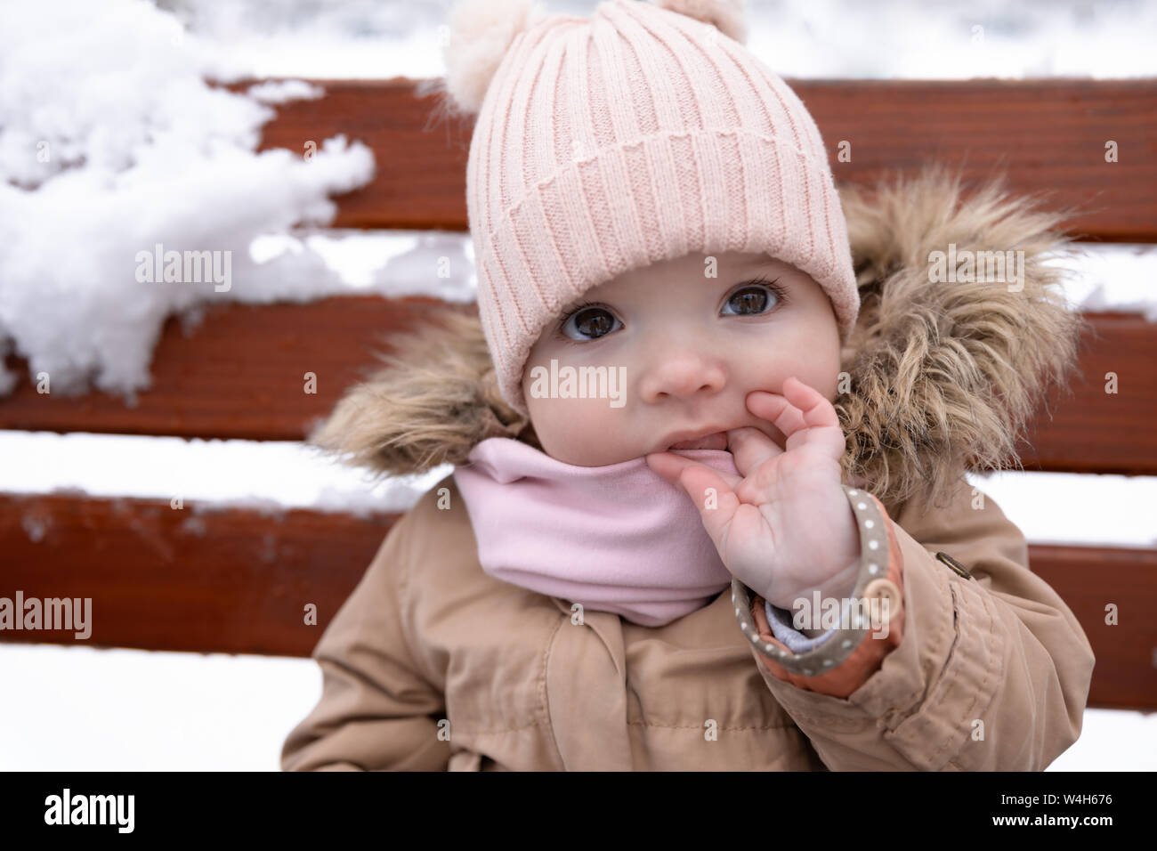 Un petit enfant est assis sur le banc. L'hiver à l'extérieur. Banque D'Images