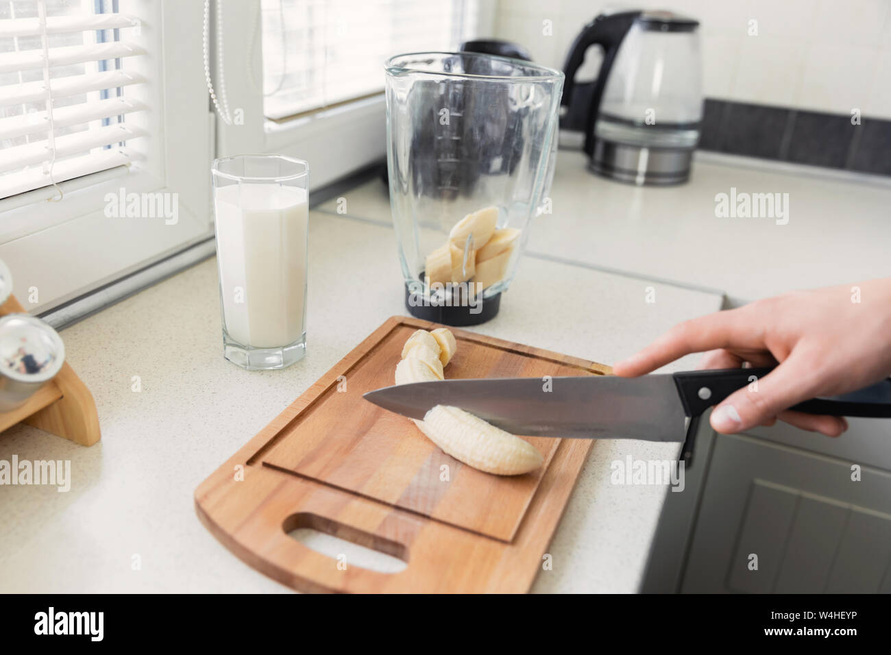 Un jeune homme prépare un smoothie de lait et de fruits frais pour le petit-déjeuner. Il mène une vie saine. Banque D'Images