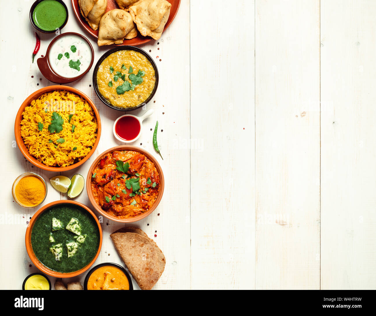 Des plats de cuisine indienne : tikka masala, dal, paneer, samosa, chapati, chutney, épices. La nourriture indienne sur fond de bois blanc. Assortiment repas indien avec copie espace pour le texte. Vue de dessus ou de télévision. Banque D'Images