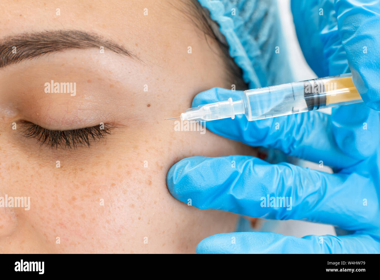 L'esthéticienne professionnelle rend les injections de vitamine de rajeunissement de la peau du visage du patient. Une jeune fille est en cours de traitement de spa Banque D'Images