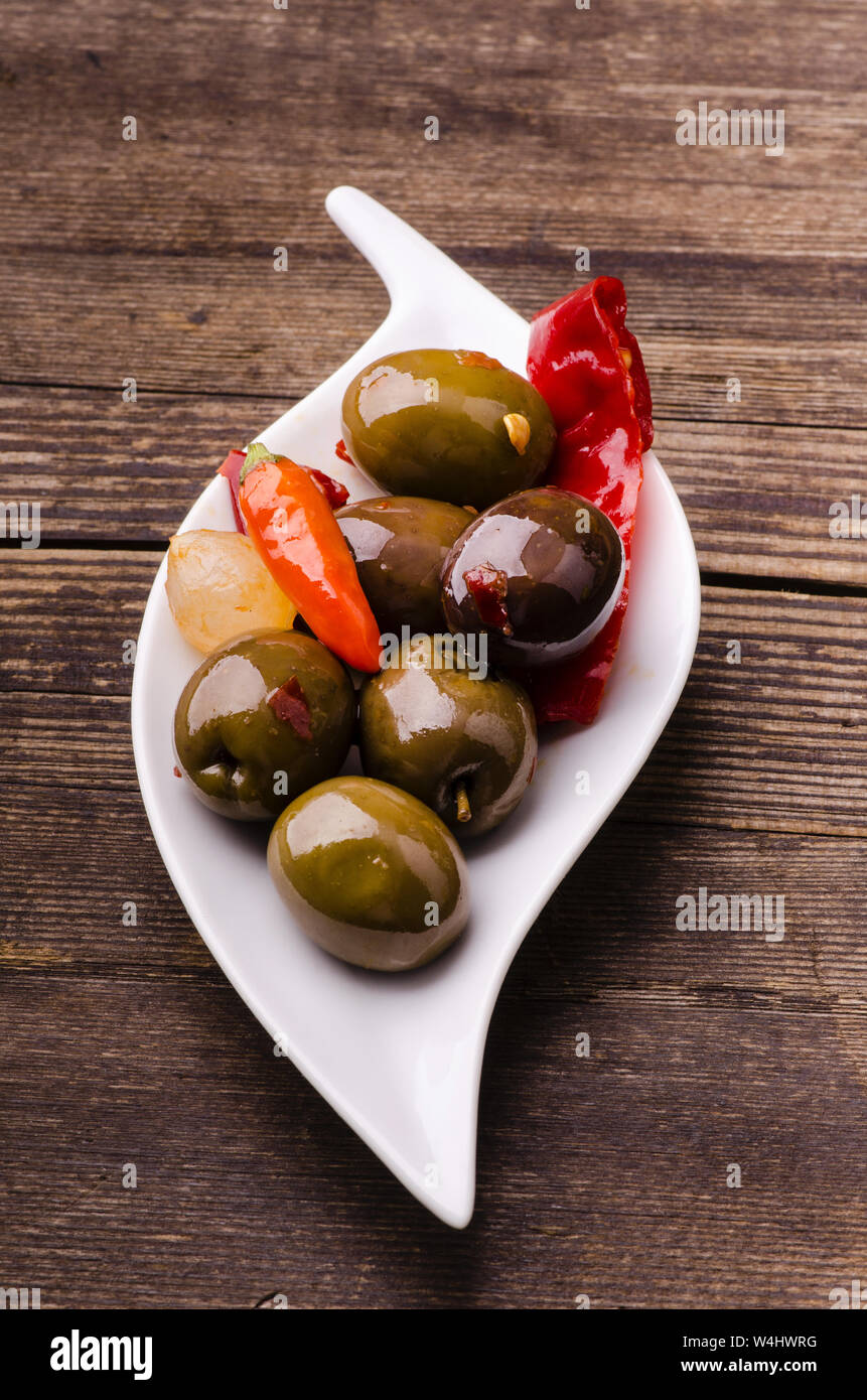 Savoureux hors-d'œuvre aux Olives vertes aromatisées avec chili épicé dans le bol en céramique blanche Banque D'Images