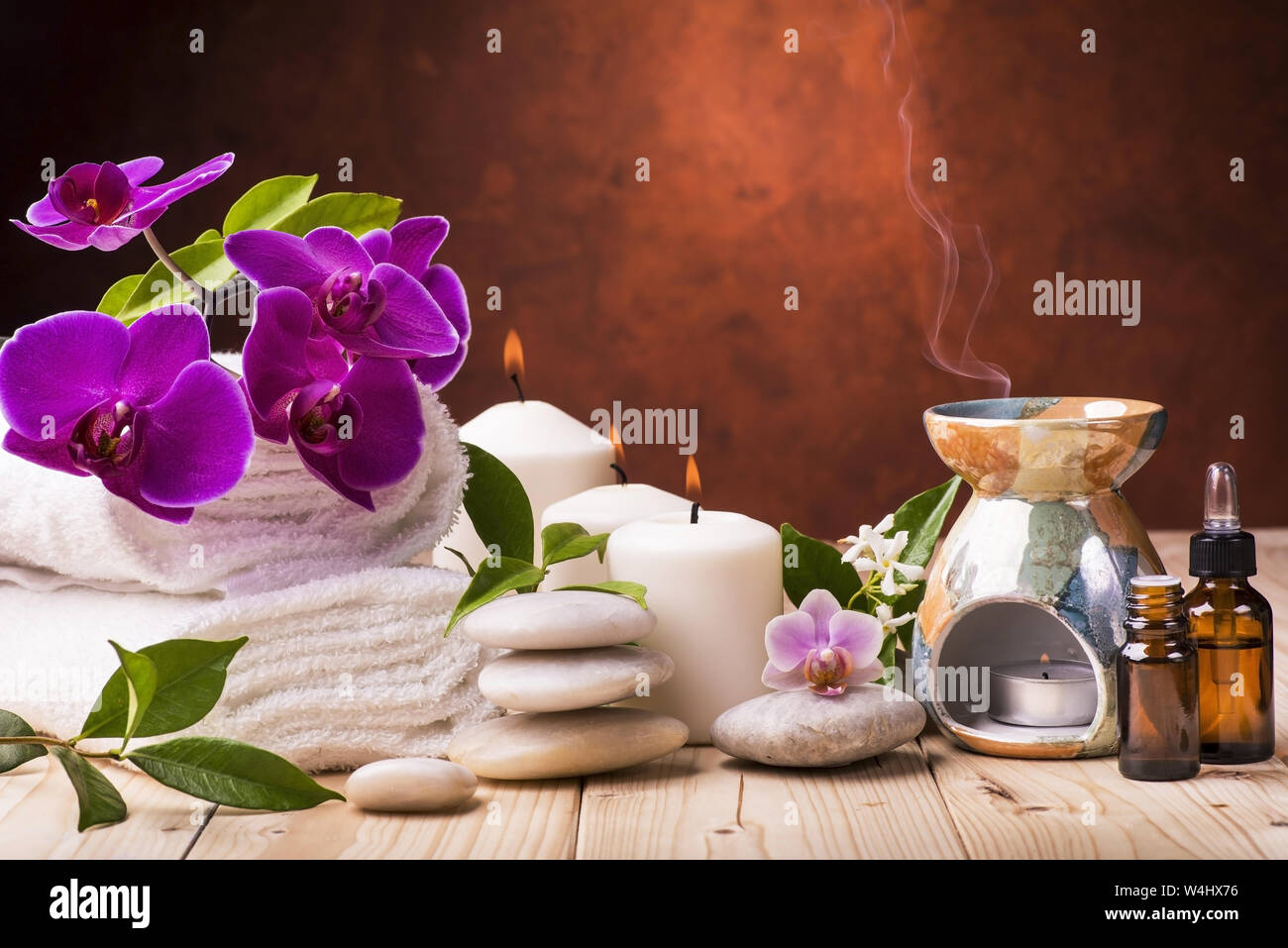 Composition avec fleurs de jasmin et d'orchidée, certaines petites bouteilles avec huiles essentielles, des bougies et de la lumière des pierres pour massage Banque D'Images