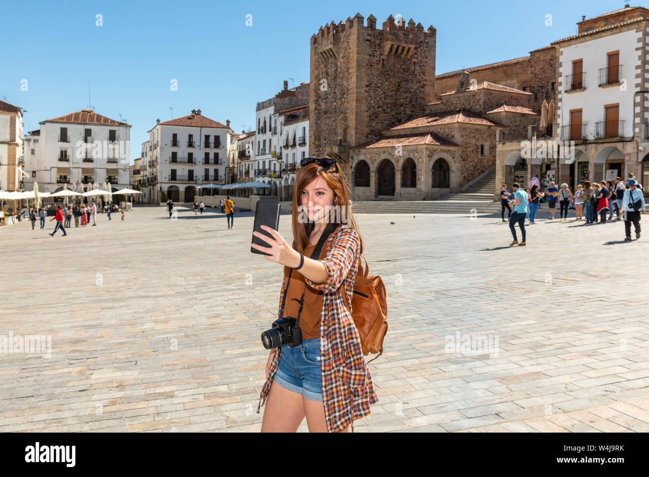 Une jeune touriste rousse avec un sac à dos fait un dans la selfies Plaza Mayor de Caceres Banque D'Images